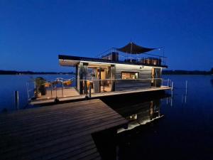 a house on a dock on a body of water at Seezeit im Hausboot mit Kamin & Sauna in Müllrose