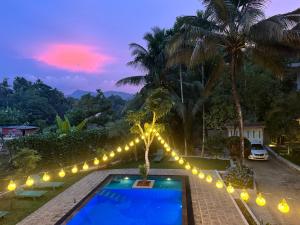 a swimming pool with lights around it at night at Heavens Holiday Resort in Kandy