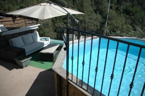 een balkon met een stoel en een parasol naast een zwembad bij La vigne sous les pins in Castagniers