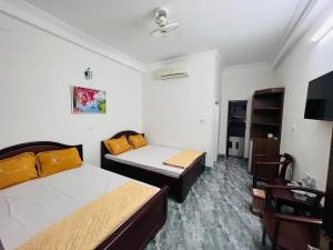 a bedroom with two beds and a table and a chair at Khách sạn Xuân Dương in Cửa Lô