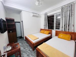 Cette petite chambre comprend deux lits et une télévision. dans l'établissement Khách sạn Xuân Dương, à Cửa Lô