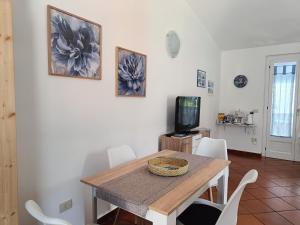 jadalnia ze stołem i krzesłami oraz telewizorem w obiekcie Appartamento Sole w mieście Cala Gonone