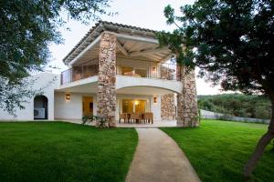 ein großes Haus mit Balkon und Rasen in der Unterkunft Villas Resort Wellness & SPA in Castiadas