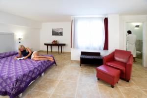 Una donna sdraiata su un letto in una camera da letto di Villas Resort Wellness & SPA a Castiadas