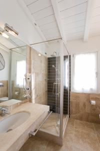 La grande salle de bains est pourvue d'une baignoire et d'une douche. dans l'établissement Villas Resort Wellness & SPA, à Castiadas