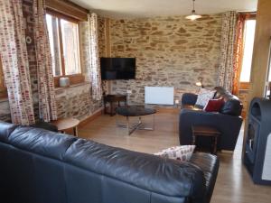 a living room with a leather couch and a tv at Gite de Tournieres in Tournières