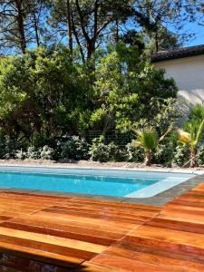 una piscina con suelo de madera y árboles en LA VILLA DES PINS, en Lacanau-Océan