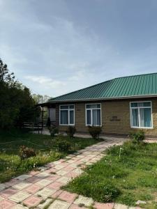 ein Backsteinhaus mit grünem Dach in der Unterkunft Ай хаус in Tscholponata
