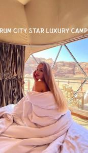 a woman in a dress laying on a bed at Rum city Star LUXURY Camp in Wadi Rum