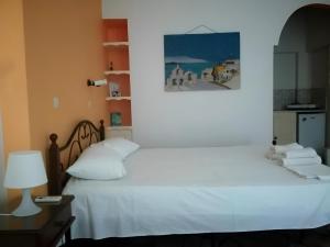 a bedroom with a white bed with a picture on the wall at Vocamvilia Apartments in Kamari