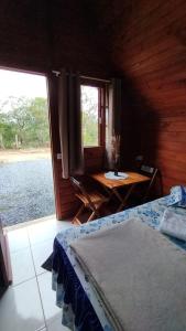 een slaapkamer met een bed, een tafel en een raam bij Pousada Cabanas in Alto Paraíso de Goiás