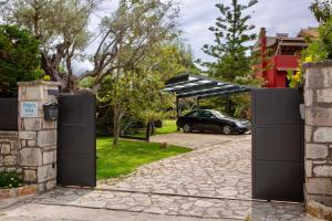 un cancello con un'auto parcheggiata in un vialetto di Poly's Villa Lefkada a Città di Lefkada