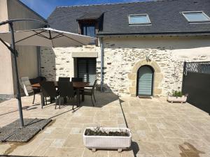 a patio with an umbrella and a table and chairs at GITES DE KERFETAN in Moréac