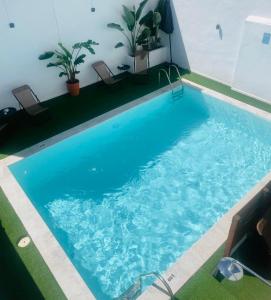 a swimming pool with blue water in a building at La Casa de Carmen in Castilleja de la Cuesta