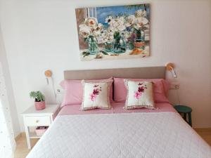 Un dormitorio con una cama rosa con almohadas y una pintura en Apartamentos Hondahouse en Playa Honda Mar Menor, 1 o 2 dormitorios, en Playa Honda