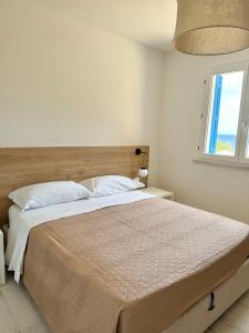 a white bedroom with a large bed with a window at Bilocale Bellavista in Marettimo