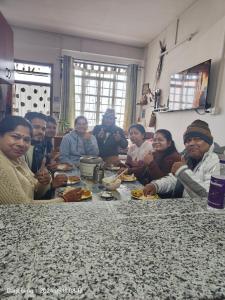 Un groupe de personnes assises autour d'une table et mangeant de la nourriture dans l'établissement Vilasa Homestay, à Darjeeling