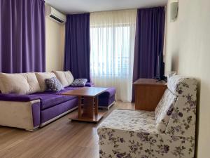 ein Wohnzimmer mit einem lila Sofa und einem Tisch in der Unterkunft Hotel Atol in Sonnenstrand
