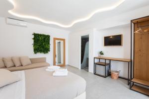 ein weißes Zimmer mit einem Bett und einem Sofa in der Unterkunft Agia Anna Beachfront Boutique in Strand Paraga