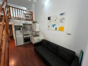 a living room with a black couch and a kitchen at Centrally Apartment in El Raval in Barcelona