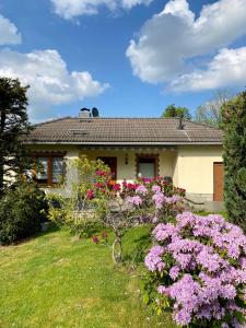 a house with pink flowers in front of a yard at Ferienhaus Waldoase in Ilsenburg