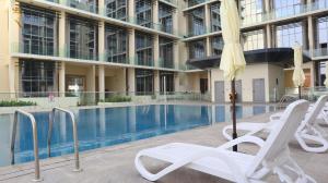a pool in a building with chairs and an umbrella at MasdarCity Bliss 2BR apartment in Abu Dhabi