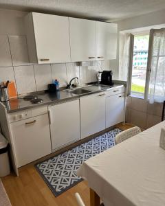 a kitchen with white cabinets and a sink and a table at Bom descanso in Ennenda