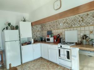 una cocina con armarios blancos y electrodomésticos blancos en Gîte les deux sources au pied du Vercors, en Saint-Laurent-en-Royans