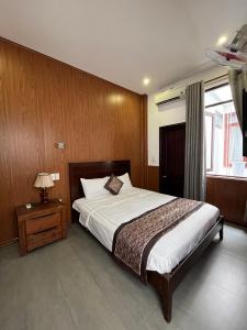 a bedroom with a bed and a table with a lamp at Kha Hostel in Hue