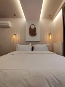 a bedroom with a white bed and two lights at Meteora Gold and Glass in Kalabaka