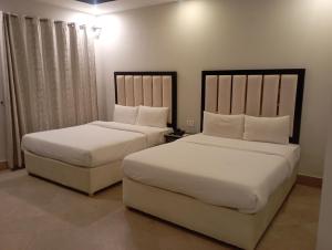 two beds in a hotel room with white sheets at Guest Rest House in Islamabad