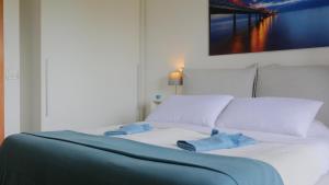 ein weißes Bett mit zwei blauen Handtüchern darauf in der Unterkunft Appartamento [Golden Hour] Marina di Pietrasanta in Marina di Pietrasanta