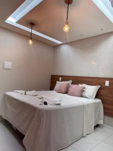 1 dormitorio con 1 cama grande con almohadas blancas y rosas en Pousada Beija Flor en Maceió