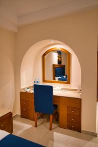 a bathroom with a vanity with a mirror and a blue chair at Tropitel Dahab Oasis in Dahab