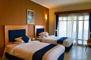 a hotel room with two beds and a window at Tropitel Dahab Oasis in Dahab