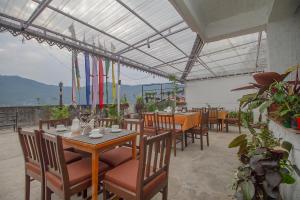 ガントクにあるPalri Boutique Hotelの木製のテーブルと椅子、旗が並ぶレストラン