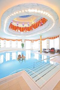 a large swimming pool with two people in it at Wellness Privathotel Post an der Therme in Badenweiler