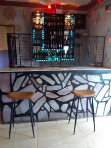 a bar with two stools and a counter with alcohol bottles at NIGHT ROCKS SUITS in Jinja