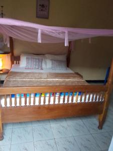 a wooden bed with a canopy in a room at NIGHT ROCKS SUITS in Jinja