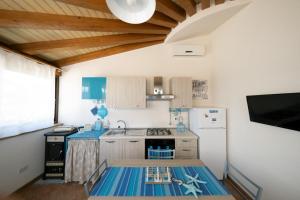 La cuisine est équipée d'un comptoir bleu et d'un réfrigérateur. dans l'établissement LOFT NICOLIZIA - Area Esterna Esclusiva con Vista Mare, à Licata