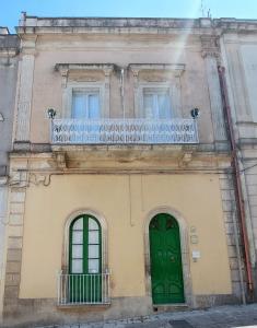 un edificio con una puerta verde y un balcón en Antica Via delle Aie, en Ruffano