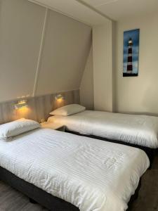 two beds in a room with a lighthouse on the wall at Waddenresidentie Ameland Zilt, een ruim 4-persoons appartement in Buren
