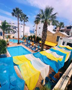 een zwembad met parasols, stoelen en palmbomen bij Kassavetis Center - Hotel Studios & Apartments in Chersonissos