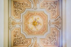 un soffitto decorato con un orologio su una parete di Villa Vandelli - Nel cuore della Motor Valley a Modena