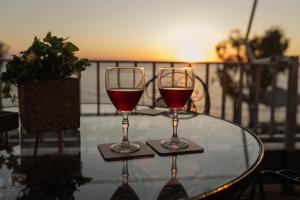 two glasses of wine sitting on a glass table at The Waves in Monodhéndrion
