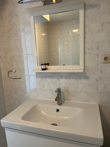 a white sink in a bathroom with a mirror at Waddenresidentie Ameland Zilt, een ruim 4-persoons appartement in Buren