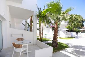 a white house with a table and a palm tree at Lefko Suites in Hanioti