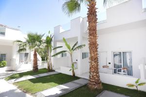 a white building with palm trees in front of it at Lefko Suites in Hanioti