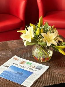 een vaas met bloemen op een tafel naast een krant bij Hotel Moulin Plaza in Parijs