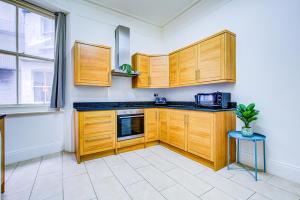 a kitchen with wooden cabinets and a microwave at Dubai Media City Convenient Apartments in Dubai